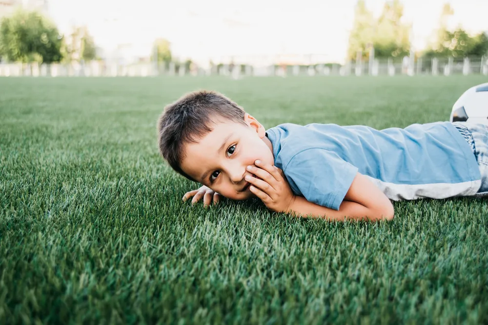 Niños jugando descalzos en pasto sintético anti-calor, seguro para mascotas y familias en Querétaro
